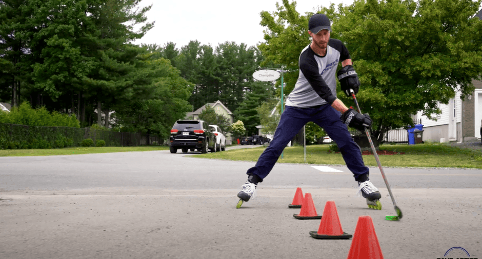A hockey player stick handling a hockey puck between cones with his rollerblades on