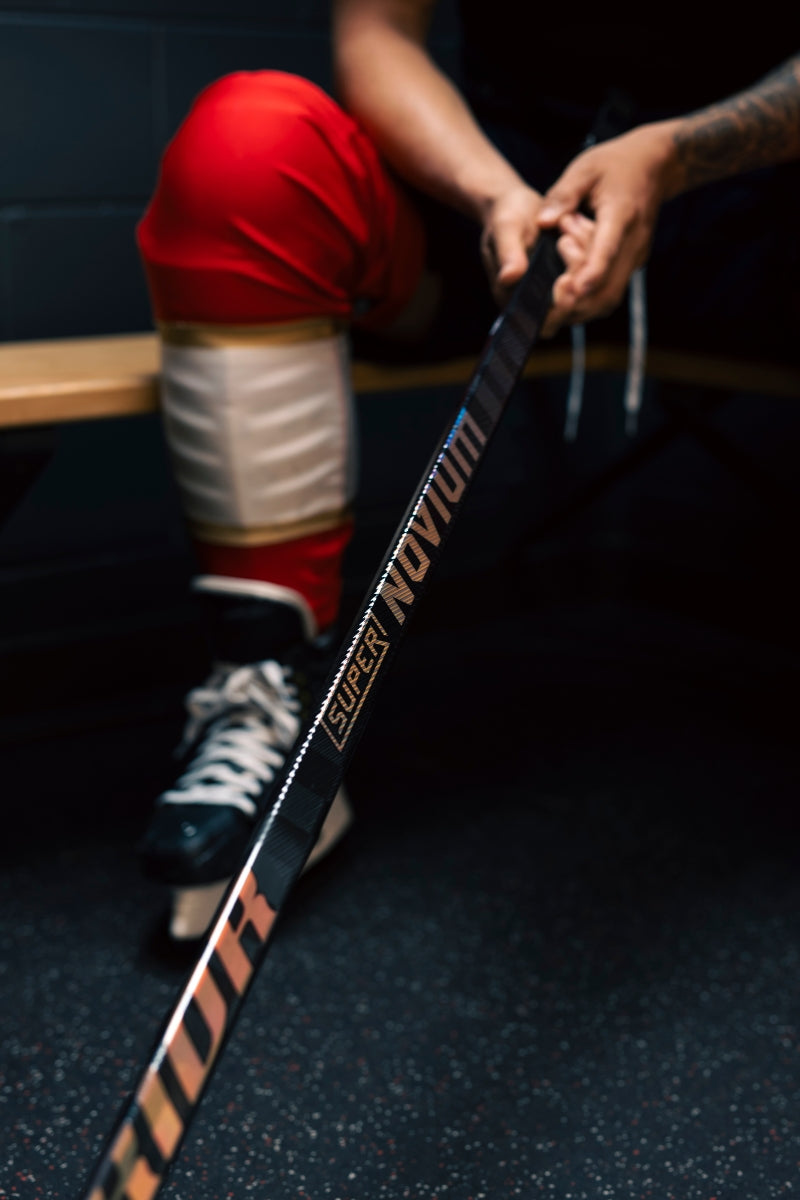 A hockey player holding the Warrior Super Novium hockey stick